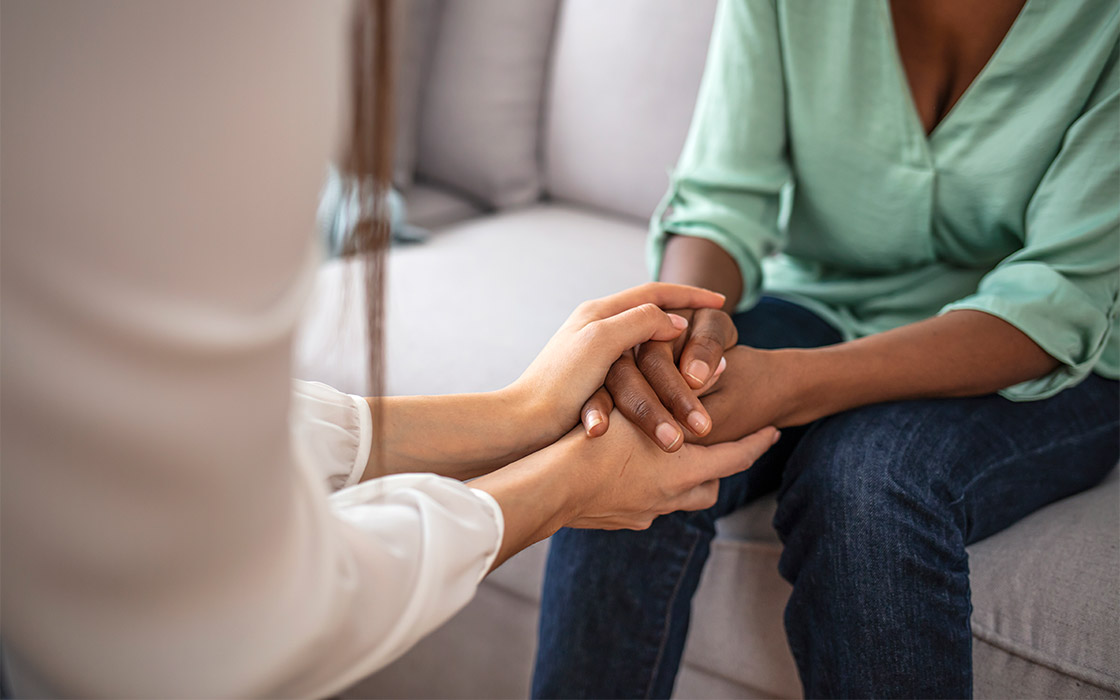 A mental health professional holding hands with a patient